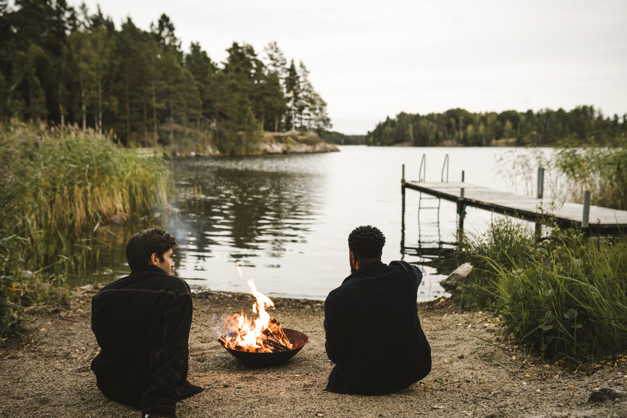 Två personer vid en lägereld vid en sjö.